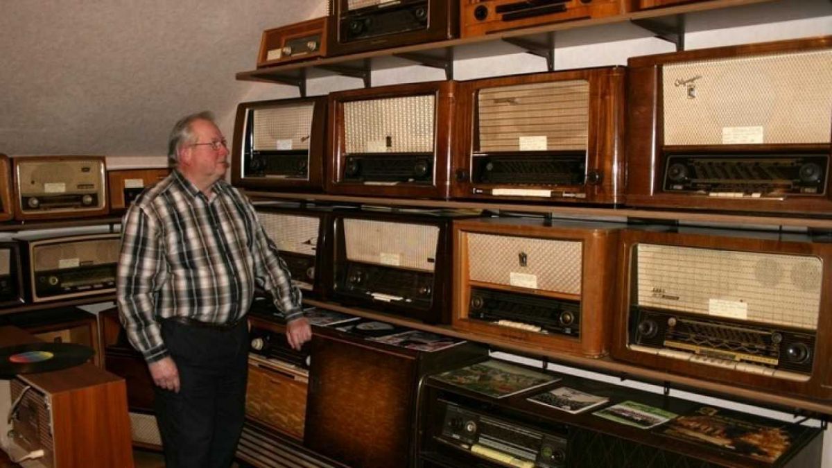 Reinhard Flöper vor einigen alten Radios, die im Vergleich zu modernen Geräten riesengroß erscheinen. von s: Jill Arens