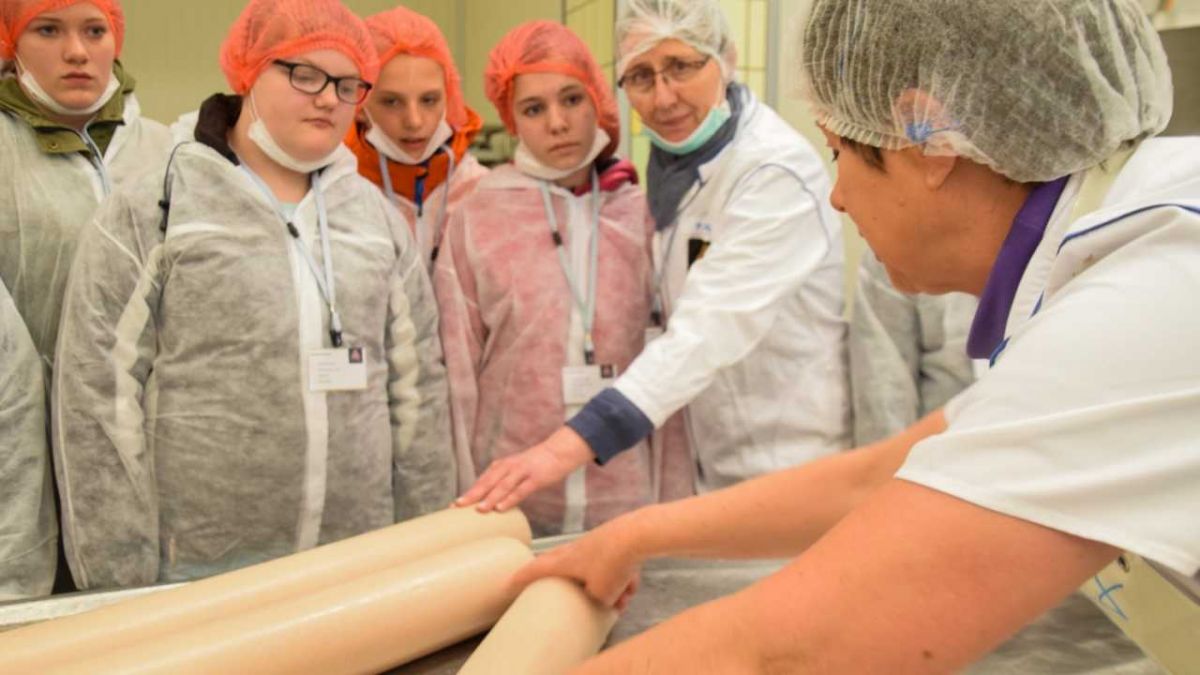 Von der Füllmaschine auf den Tisch und in den "Slicer": Im Produktionsbereich für Brühwurst erklären eine Angestellte und Personalleiterin Petra Palla (2. von rechts), wie Wurst für den SB-Bereich hergestellt und verarbeitet wird. von s: Sven Prillwitz