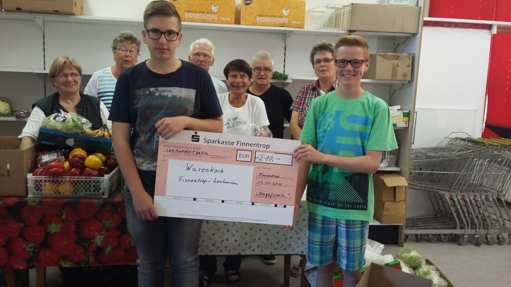Leon Berghaus und Nico Voß überreichen den Mitarbeitern des Warenkorbes Finnentrop-Lenhausen einen Spendenscheck.
