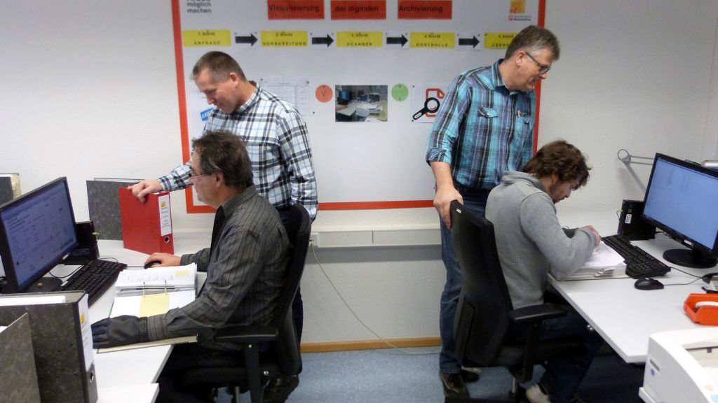 Markus Hanses (stehend l.) und Achim Scheckel (stehend r.) beobachten mit Freude die Weiterentwicklung der Mitarbeiter in der Abteilung „Digital Plus“. von Werthmann-Werkstätten
