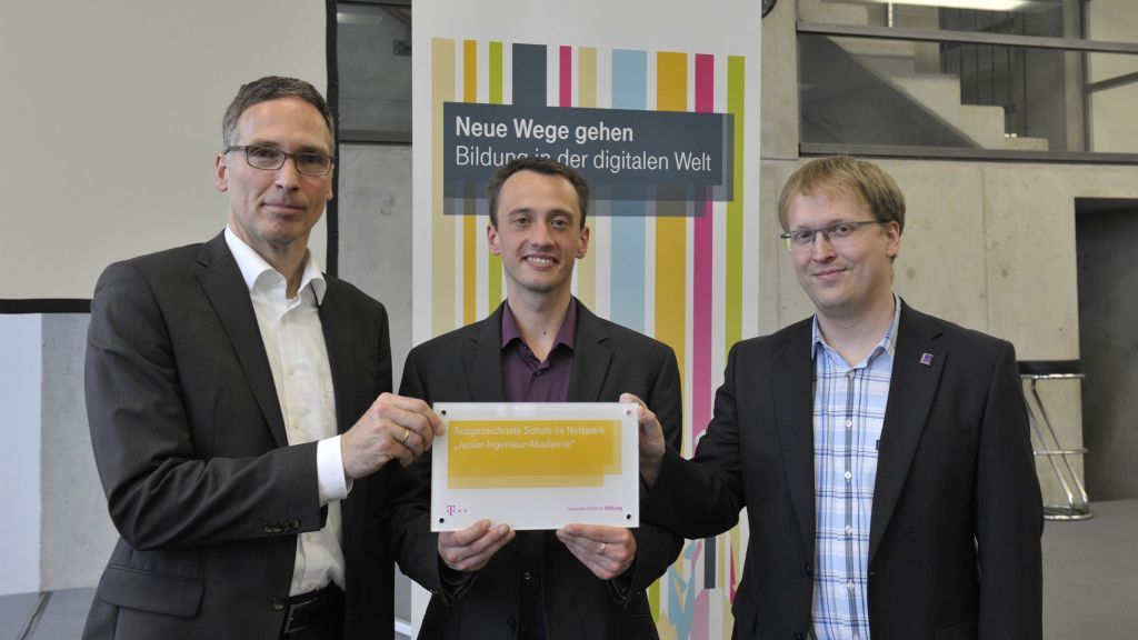 Die Lehrer des Gymnasiums Maria Königin, Matthias Walter und André Bertels, erhalten die Auszeichnung vom Vorsitzenden der Jury, Dr. Gerd Hanekamp. von Deutsche Telekom Stiftung