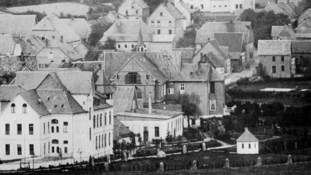 Diese Aufnahme aus dem Jahre 1910 zeigt die rückwärtige Ansicht der fertiggestellten Gebäude der Schwersternniederlassung mit dem Totenkapellchen und dem neu angelegten Kreuzweg. von GFO