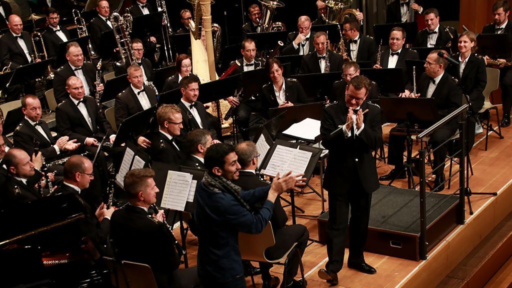 Begrüßung des ersten „Special Guest" für diesen Abend: Das Musikkorps der Bundeswehr heißt Pianist und Sänger Aeham Ahmad auf der Bühne der Stadthalle Olpe willkommen. von Thomas Fiebiger
