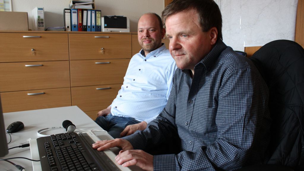 Frank Leifermann (rechts) mit Benedikt Hilchenbach an seinem Arbeitsplatz. Unterhalb der Tastatur ist die Braillezeile zu erkennen, mit der der blinde Praktikant mit den Fingern „liest“. von Kreis Olpe