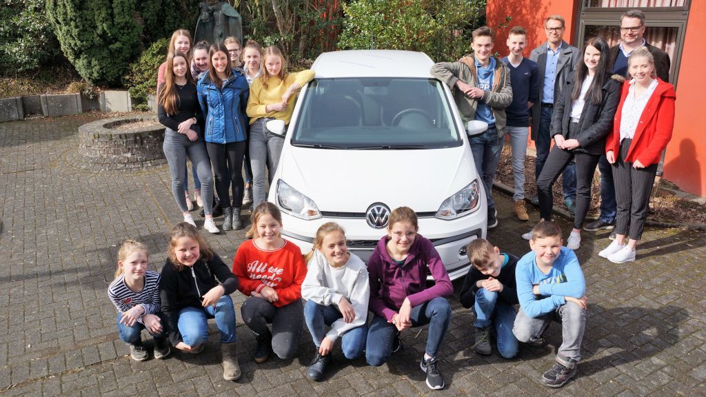 Schulleiter Jan Fabian Borys und Steffen Baumhoff vom Autohaus Baumhoff präsentierten mit Schülern des Gymnasiums Maria Königin einen neuen VW up als Hauptpreis der Schul-Lotterie. von privat