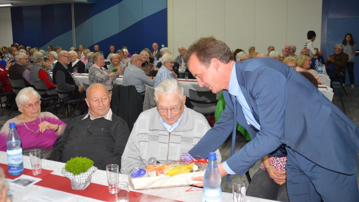 Bürgermeister Bernd Clemens überreicht dem ältesten Teilnehmer des Seniorennachmittages Franz Schmidthöfer einen Frühstückskorb. von Nicole Voss