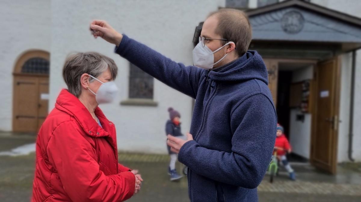 Gemeindereferent Alexander Müller verteilt die Asche, durch streuen aufs Haupt, auf dem Kirchplatz in Dünschede. von privat