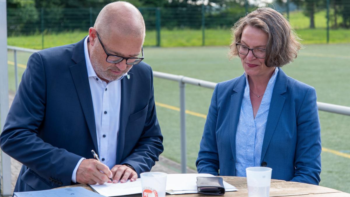 Bürgermeister Achim Henkel unterschreibt den von Ministerin Ina Scharrenbach mitgebrachten Förderbescheid. von Nils Dinkel