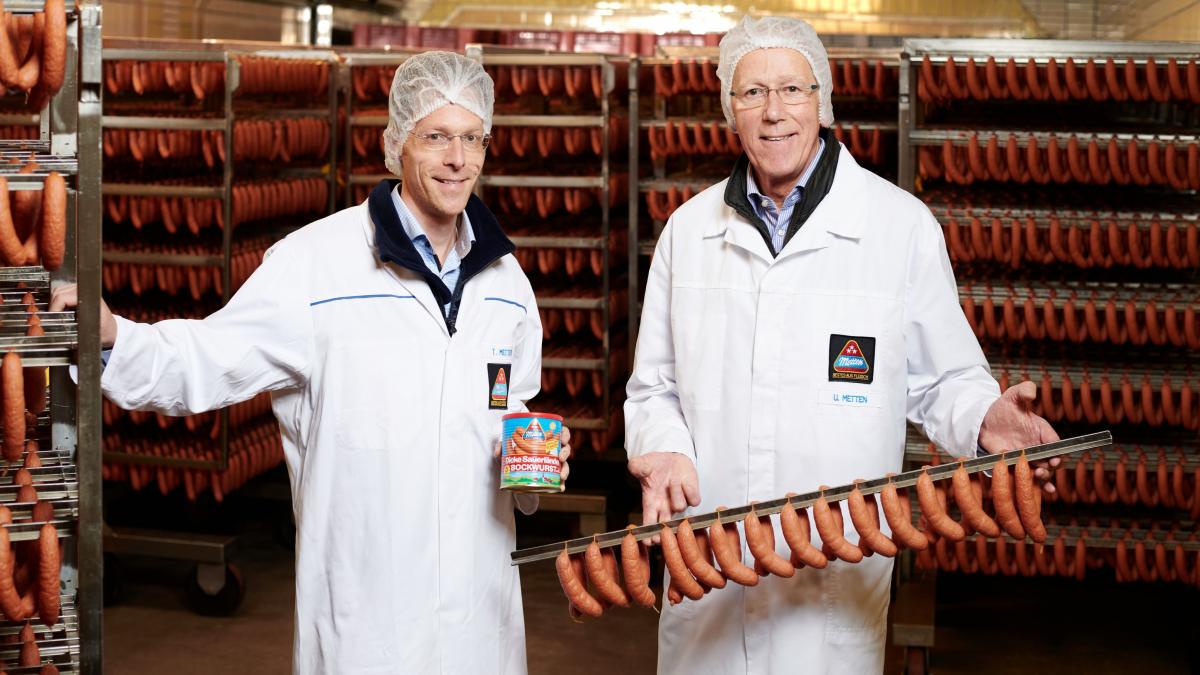 Die geschäftsführenden Gesellschafter Tobias und Ulrich Metten freuen sich über das Jubiläum der „Dicke Sauerländer“ Bockwurst. von privat