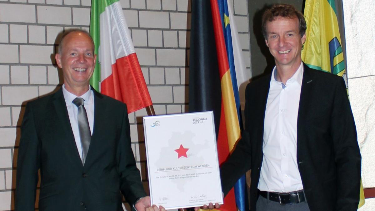 Bürgermeister Bernd Clemens (rechts) empfängt die Urkunde zum ersten Stern von Landrat Theo Melcher. von Gemeinde Wenden