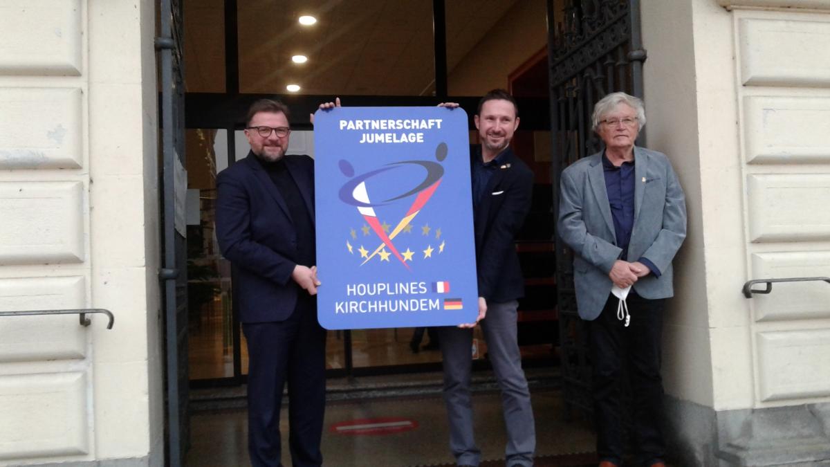 Die Bürgermeister Jean-Francois Legrand (links) und Björn Jarosz mit den frisch geprägten Schildern vor dem Rathaus in Houplines sowie Altbürgermeister Elmar Greiten (rechts). von privat