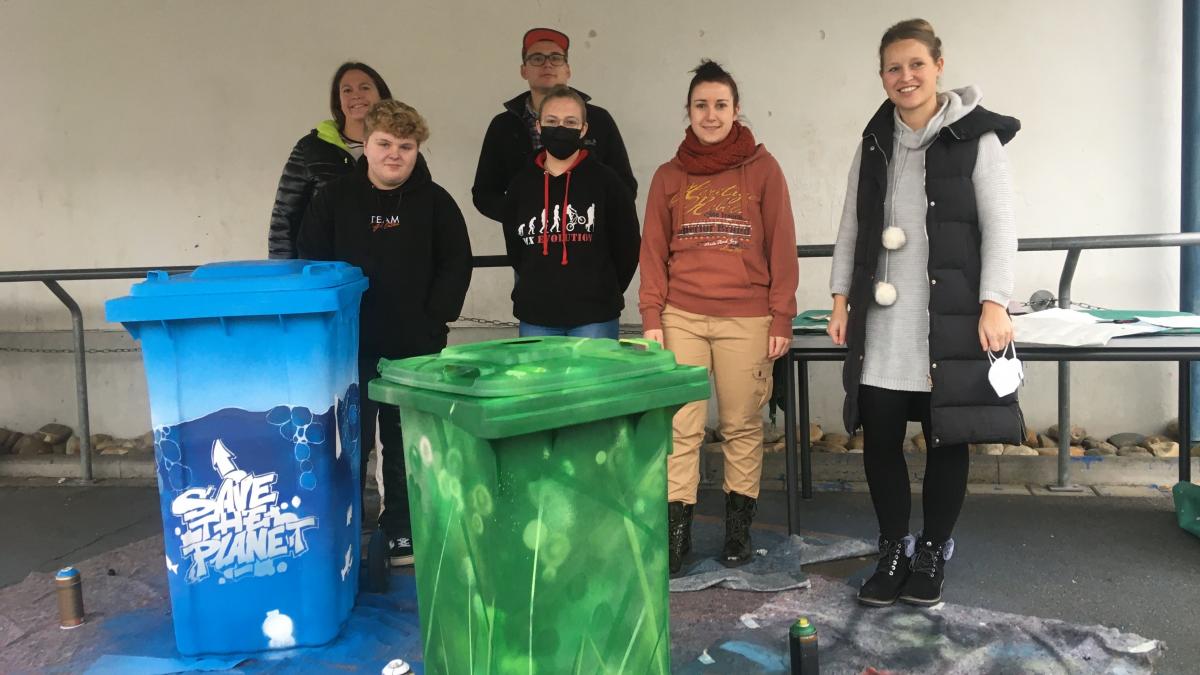 Schüler, Lehrer und der Künstler zeigen stolz die neuen Tonnen, die jetzt wahre Kunstwerke sind. von Julia Jänisch