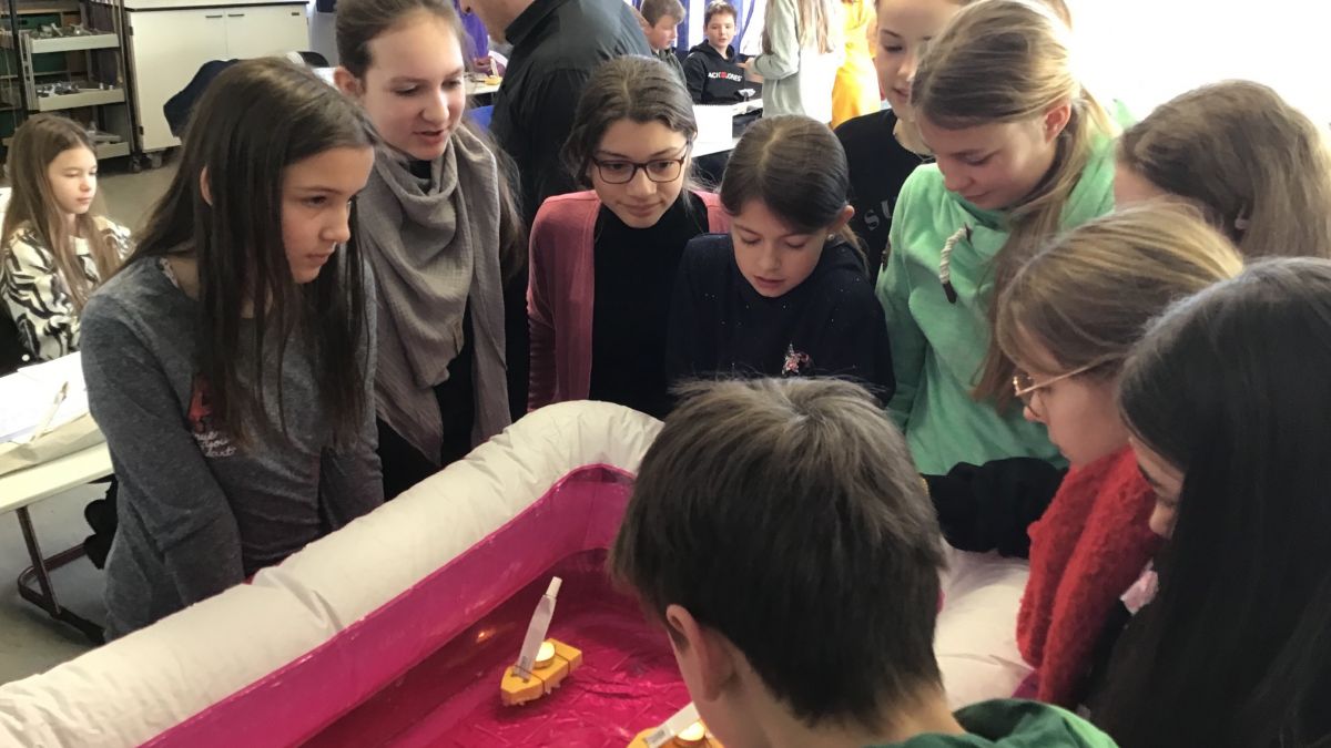 Siebtklässler lassen ihre selbst gebastelten Boote im Planschbecken im Klassenraum fahren. von privat