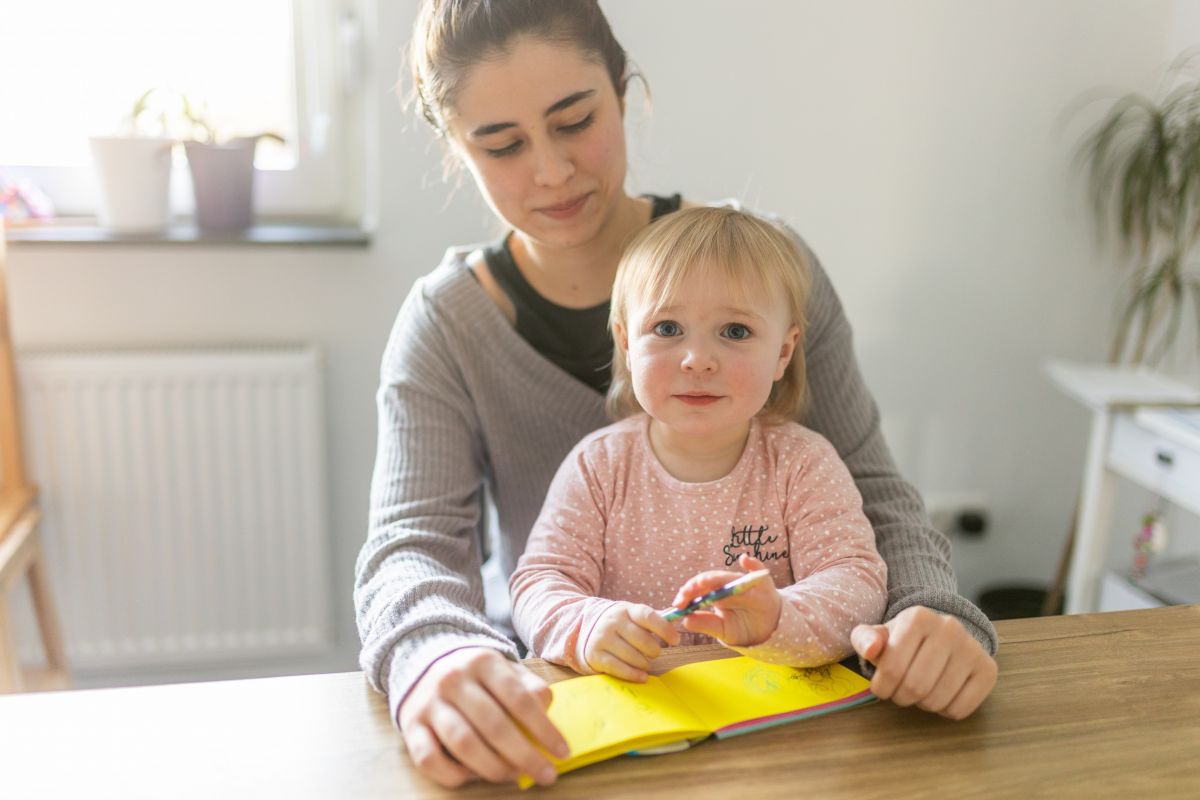 Nikola zeichnet mit Kaja (1) am Küchentisch. von Tine Schmidt