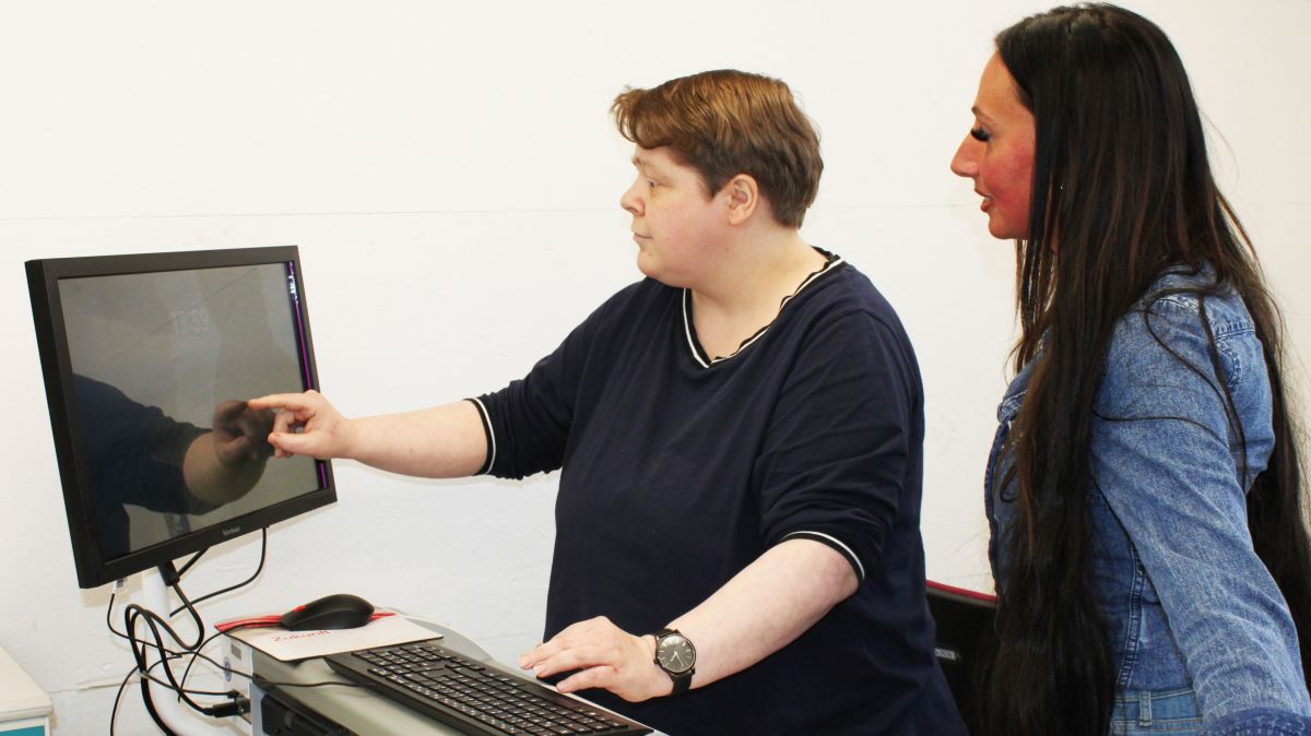 Monika Strube wird von Gruppenleiterin Julia Otterbach in die Arbeit am Großflächenscanner eingewiesen. von Caritasverband Olpe, Janine Clemens