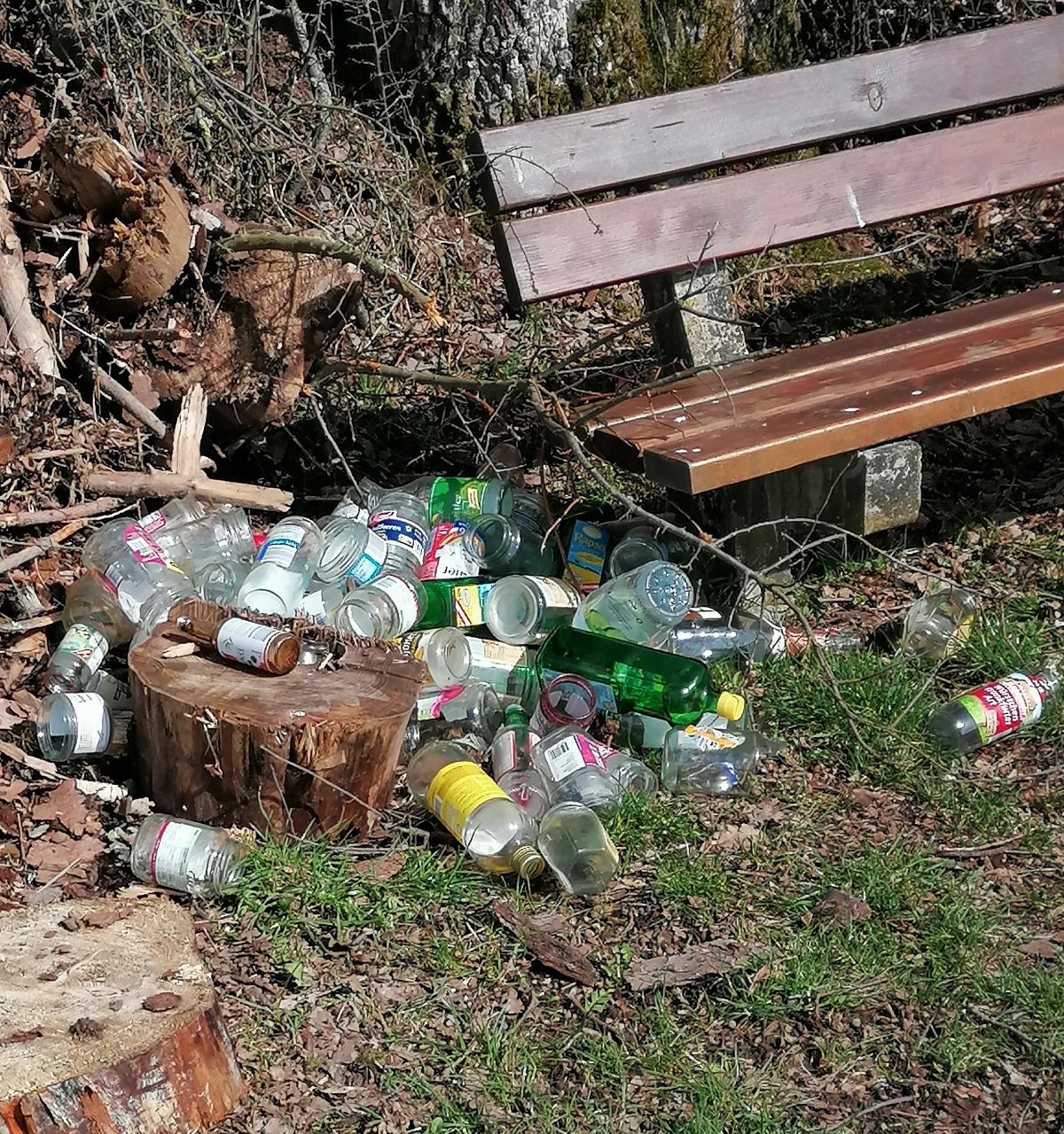 Mehrere Glasflaschen liegen neben einer Bank am Kreuzberg. von privat