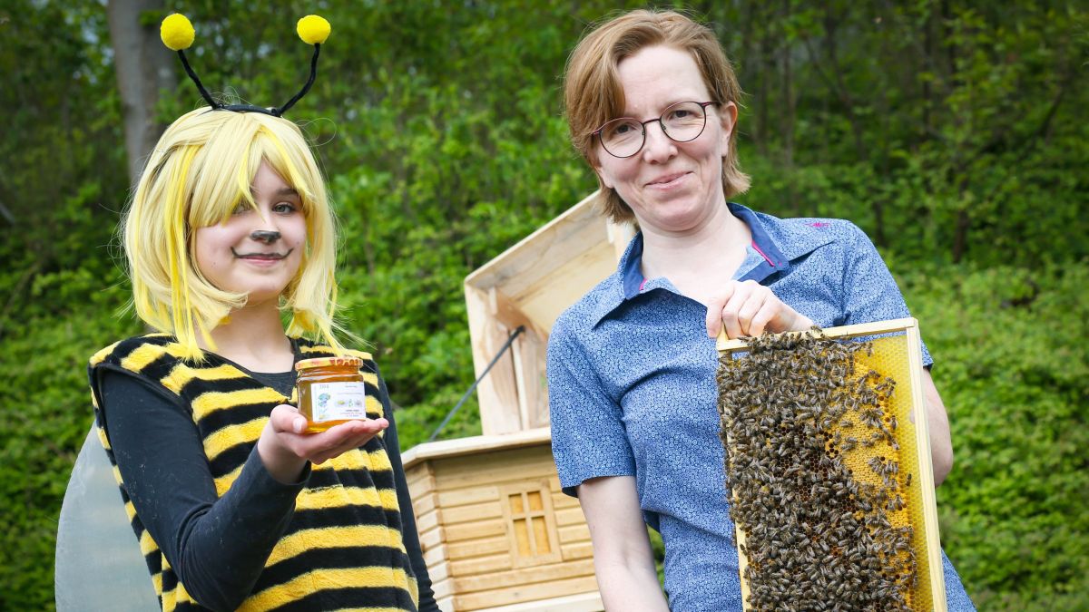 Ida (12) mit für die Premiere produzierten Honig und Imkerin Sandra Denker (rechts) mit einer Bienenwabe aus dem dahinter zu sehenden Schaukasten. von Anke Hesse