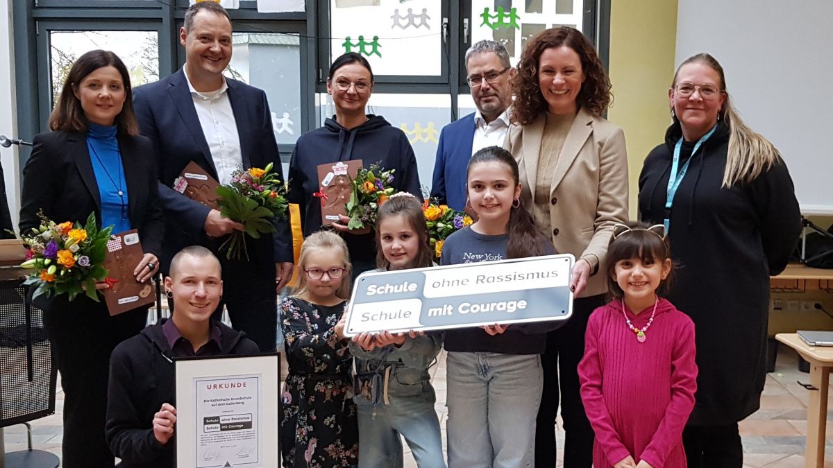 Schülerinnen der Gallenbergschule, Patrick Eberz vom Kommunalen Integrationszentrum des Kreises Olpe (vorne links), Schulleiterin Anke Olberts, Moderatorin Anne Willmes als Patin, der Olper Schulamtsleiter, Ingo Sondermann, Kirstin Wagner-Sasse als Begleiterin des Schülerparlaments, Bürgermeister Peter Weber und Schulamtsdirektorin Britta Halbe (hinten von rechts). von Kreis Olpe.