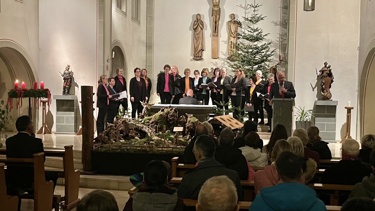 Der Frauenchor Cantiamo mit Dirigent Michael Nathen. Rechts vorne der Vorsitzende des Gemischten Chores Liederkranz Oberveischede bei seiner Moderation. von privat