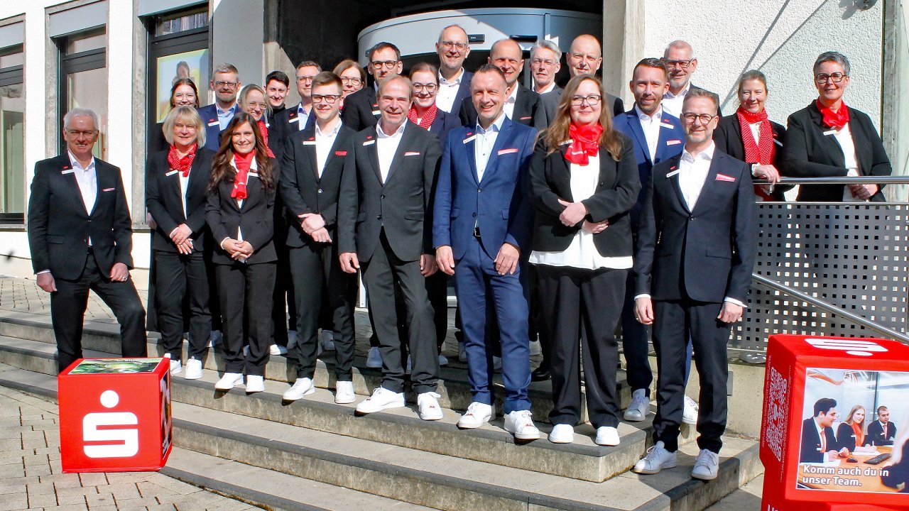 Das Foto zeigt den Vorstandsvorsitzenden Heinz-Jörg Reichmann (vorne rechts) und Vorstandsmitglied Bernd Schablowski (vorne links) mit einem Teil des Sparkassen-Teams der Geschäftsstelle Attendorn. von Sparkasse A-L-K