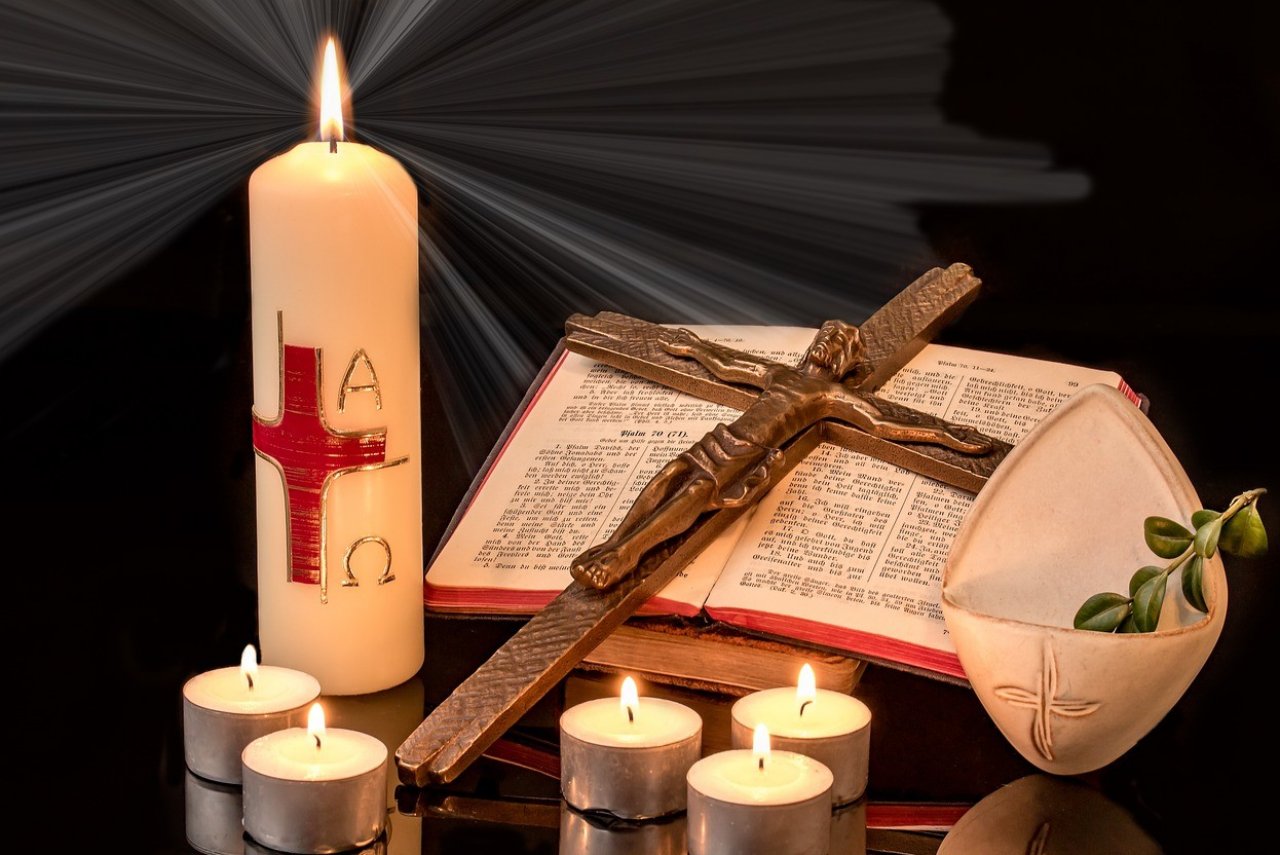 Eine Osterkerze auf einem Tisch mit Bibel und Kruifix. von Pixabay.com