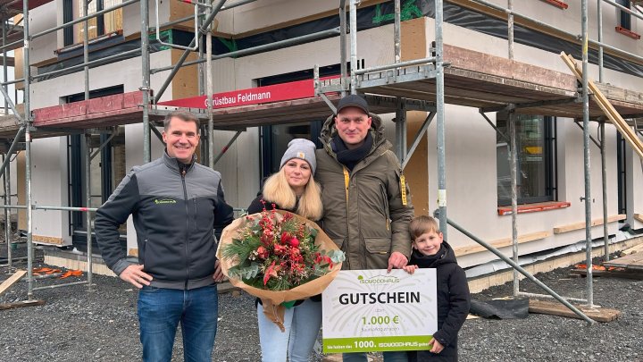 Geschäftsführer Tim Kirchhoff (links) überreicht der Baufamilie des 1.000. Isowood-Hauses einen...