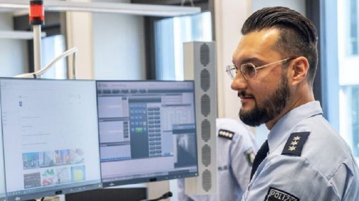 Ein Polizeibeamter vor zwei Monitoren (Symbolfoto).