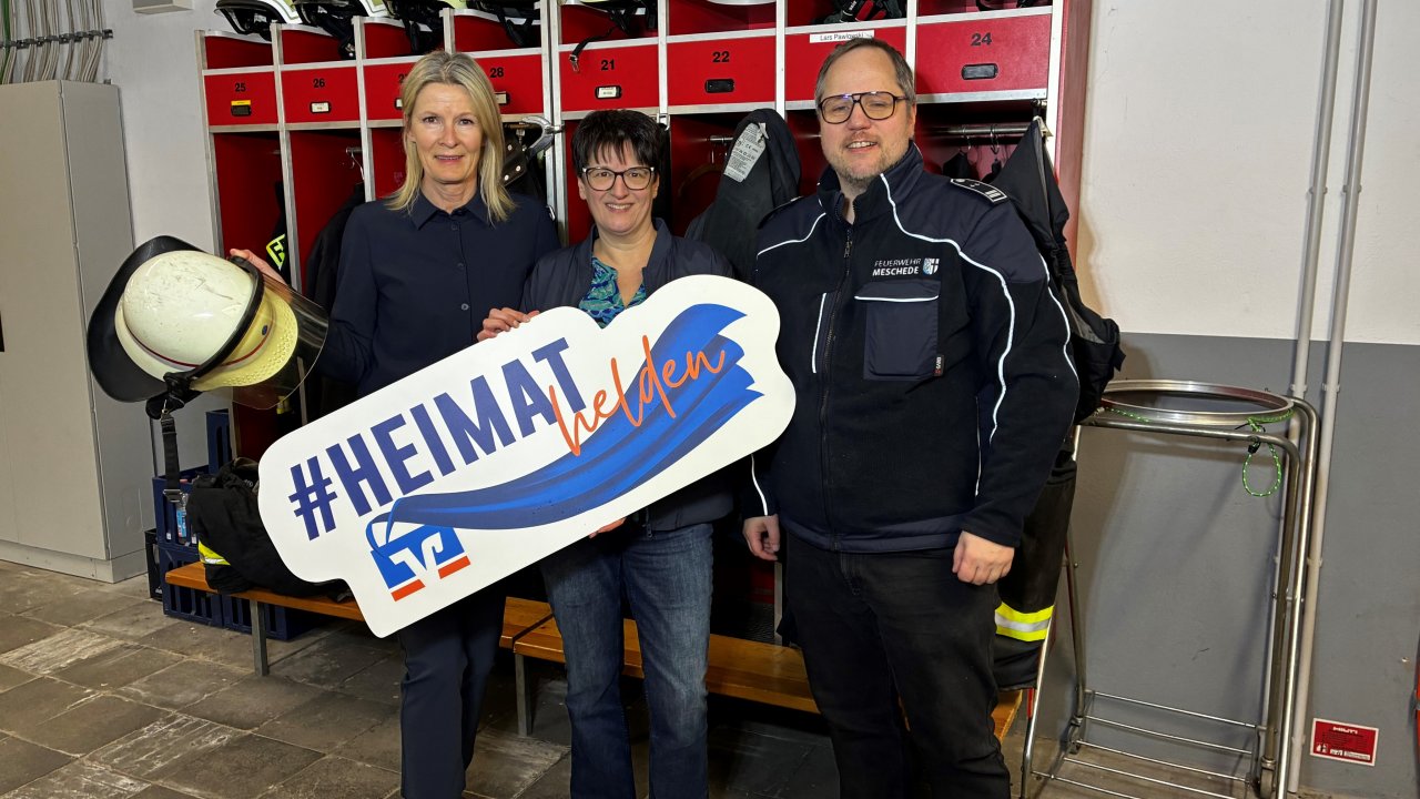 Startschuss für #Heimathelden2026: (v.l.) Claudia Wilmers und Marion Schneider (Volksbank Sauerland, Öffentlichkeitsarbeit) mit Sebastian Helleberg von der Freiwilligen Feuerwehr Meschede. von Volksbank Sauerland