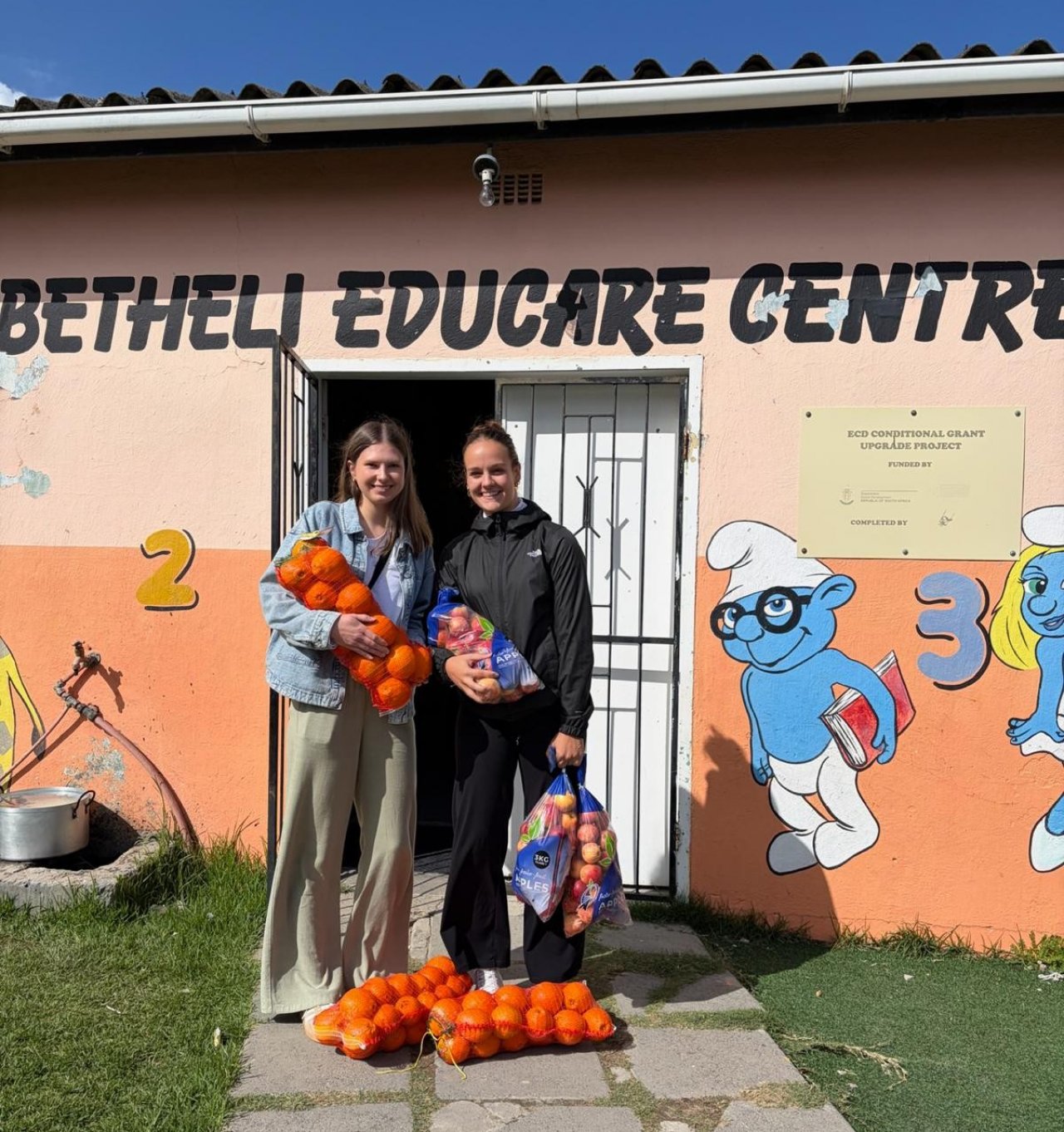 Theresa Vielhaber (r.) und Alina Schmitt-Degenhardt (l.) helfen im Rahmen eines Freiwilligenprogramms an Schulen und Kindergärten im Lwandle Township in Südafrika. Gemeinsam mit anderen Helfern sammeln sie Spenden, mit denen unter anderem frisches Obst für die Kinder gekauft werden kann. von privat