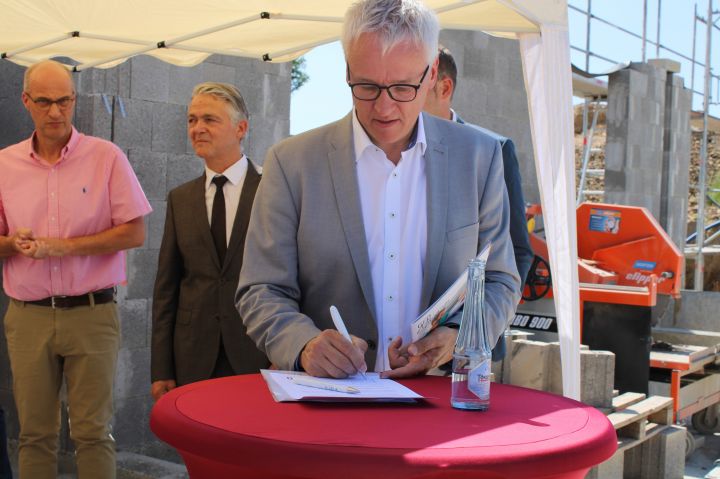 Markus Feldmann leistet seine Unterschrift auf der Urkunde für die Zeitkapsel.