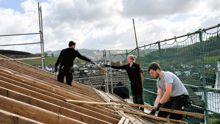 Die Dachdecker-Azubis Lukas Sieler, Emma Schwens und Lorenz Schmidt arbeiten Hand in Hand.