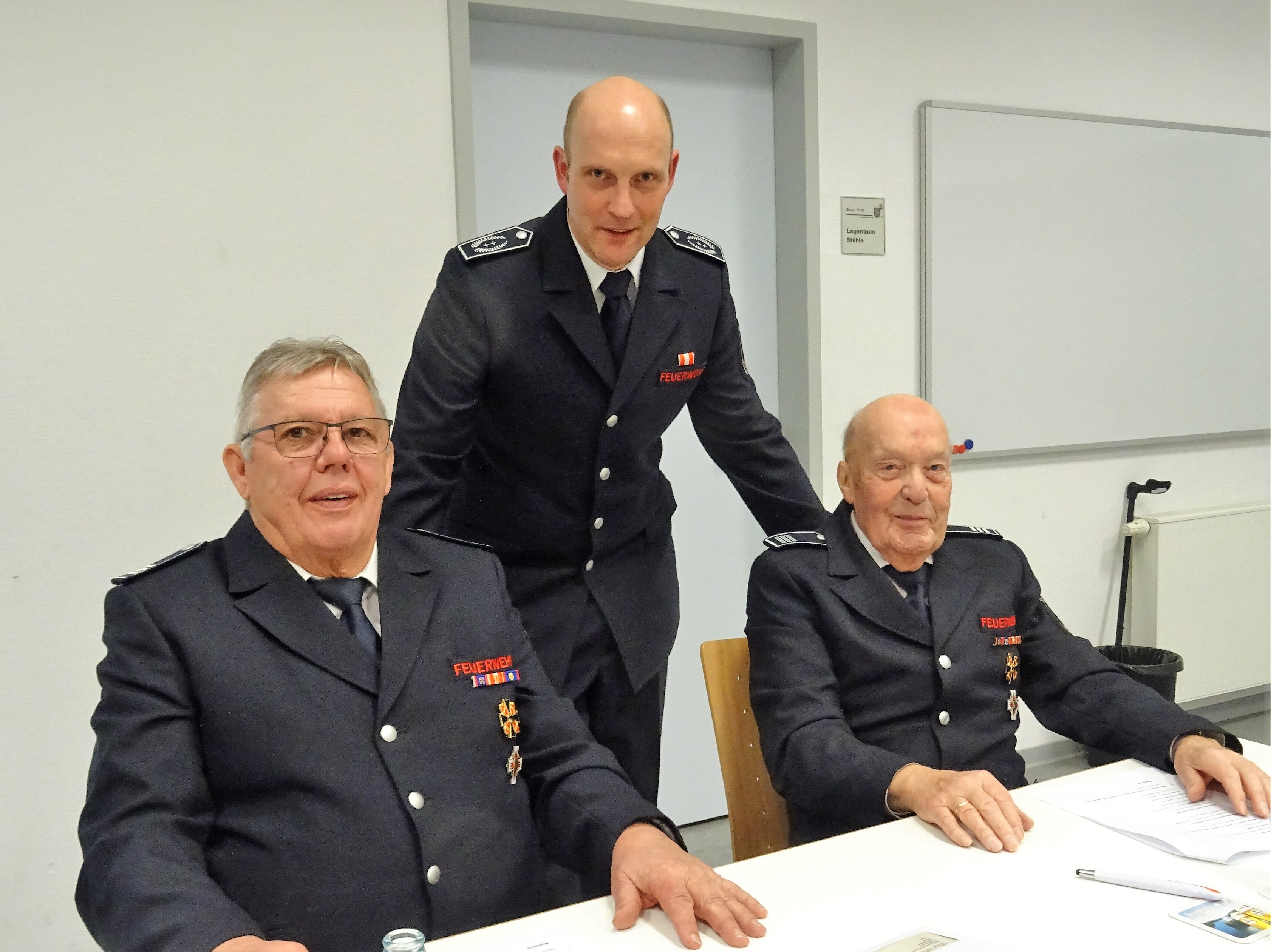 Feuerwehr-Chef Christian Hengstebeck (stehend) mit seinen beiden Vorgängern Friedrich Schulte und Willi Ledig (sitzend, von links) von Sigrid Mynar