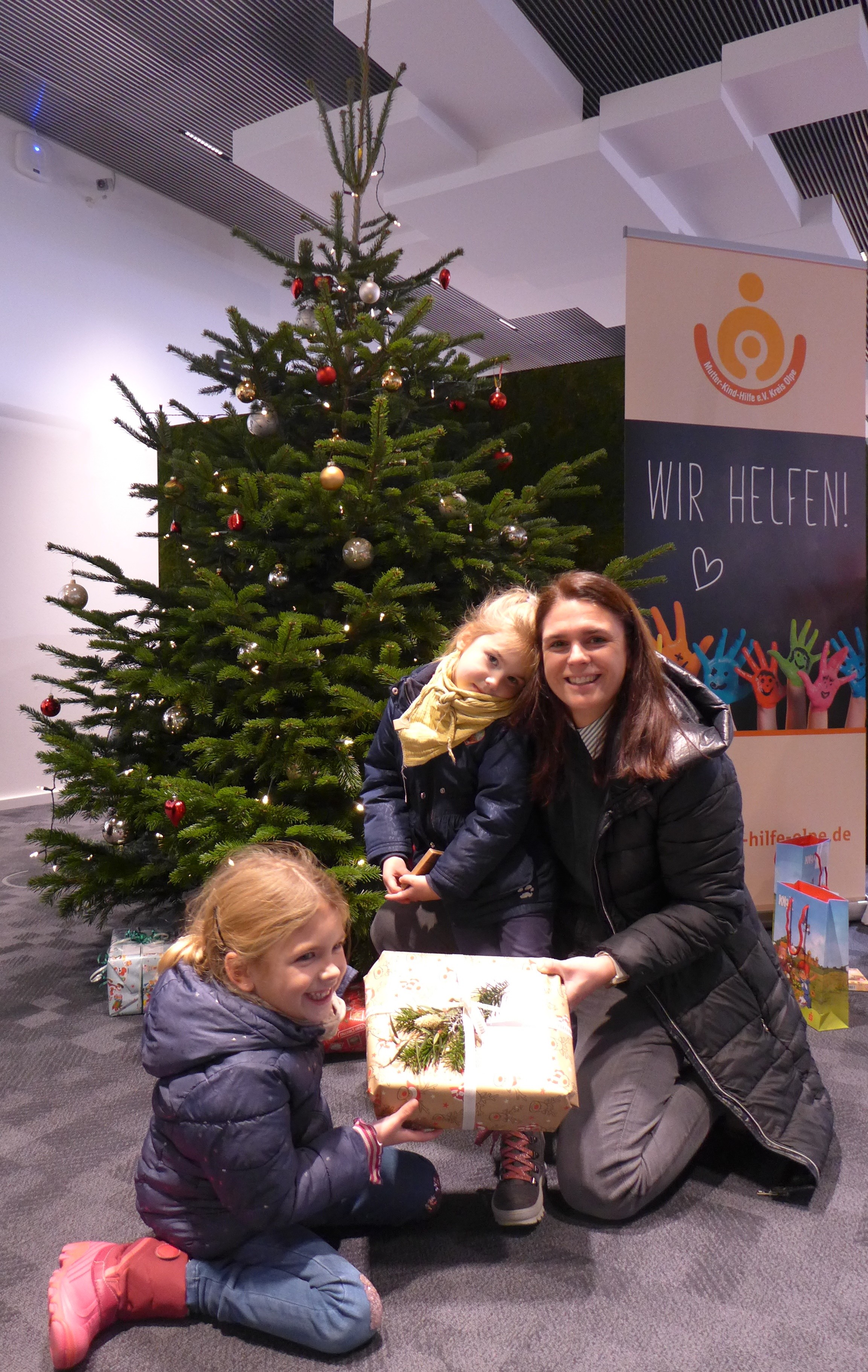 Die Schwestern Lena (6) und Paula (4) mit ihrer Mama Katharina machten bei der Wunschbaum-Aktion mit und legten die Päckchen unter den Weihnachtsbaum in der Sparkassen-Geschäftsstelle in Attendorn. von privat