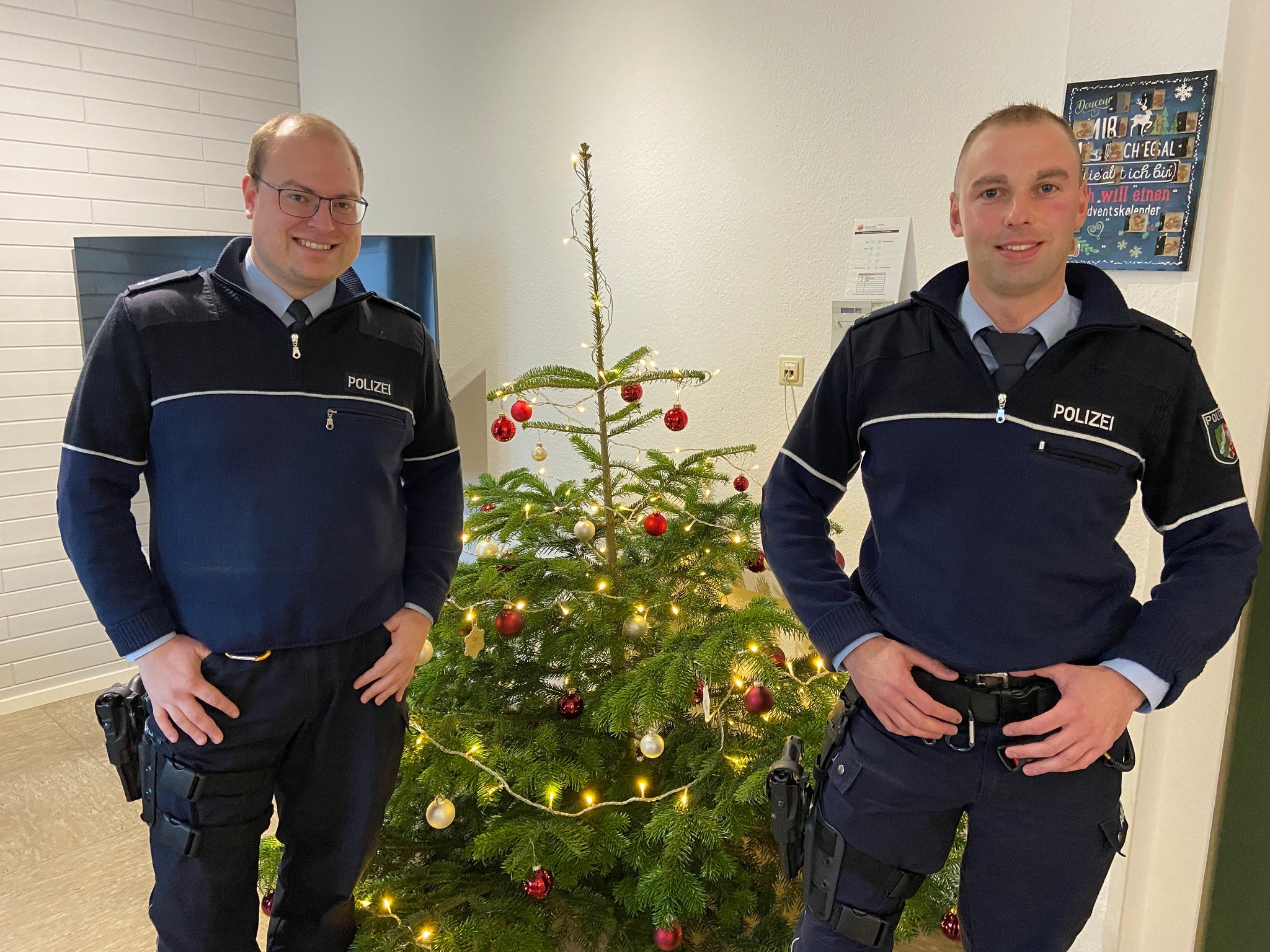 Daniel Kipp (links) und Jan Sprenger vor dem geschmückten Weihnachtsbaum der Lennestädter Wache. von Nils Dinkel
