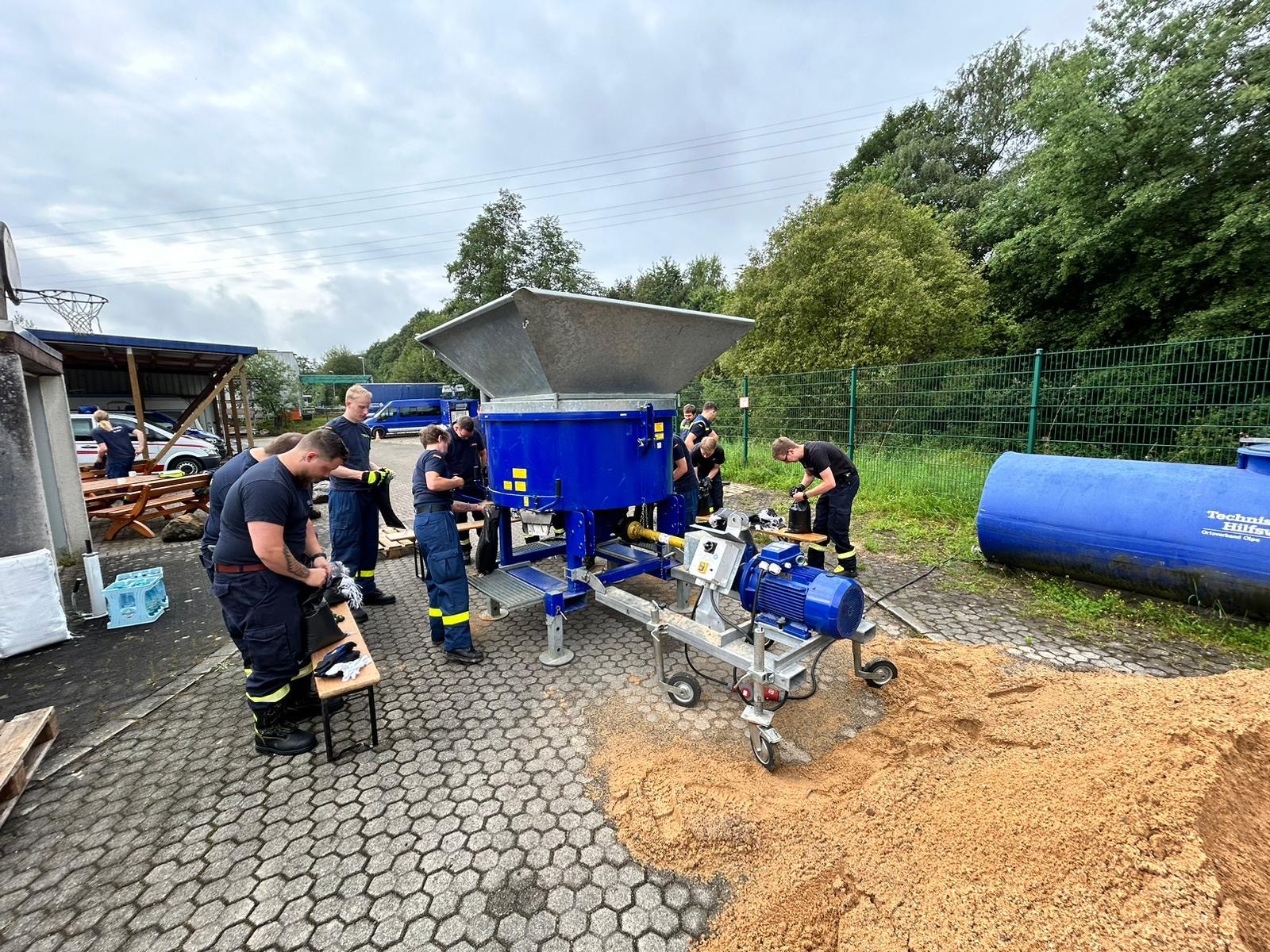 Einsatzkräfte der Feuerwehr Wenden und des THW Olpe befüllten und verteilten gemeinsam 700 Sandsäcke für die Ottfinger. von Feuerwehr Wenden