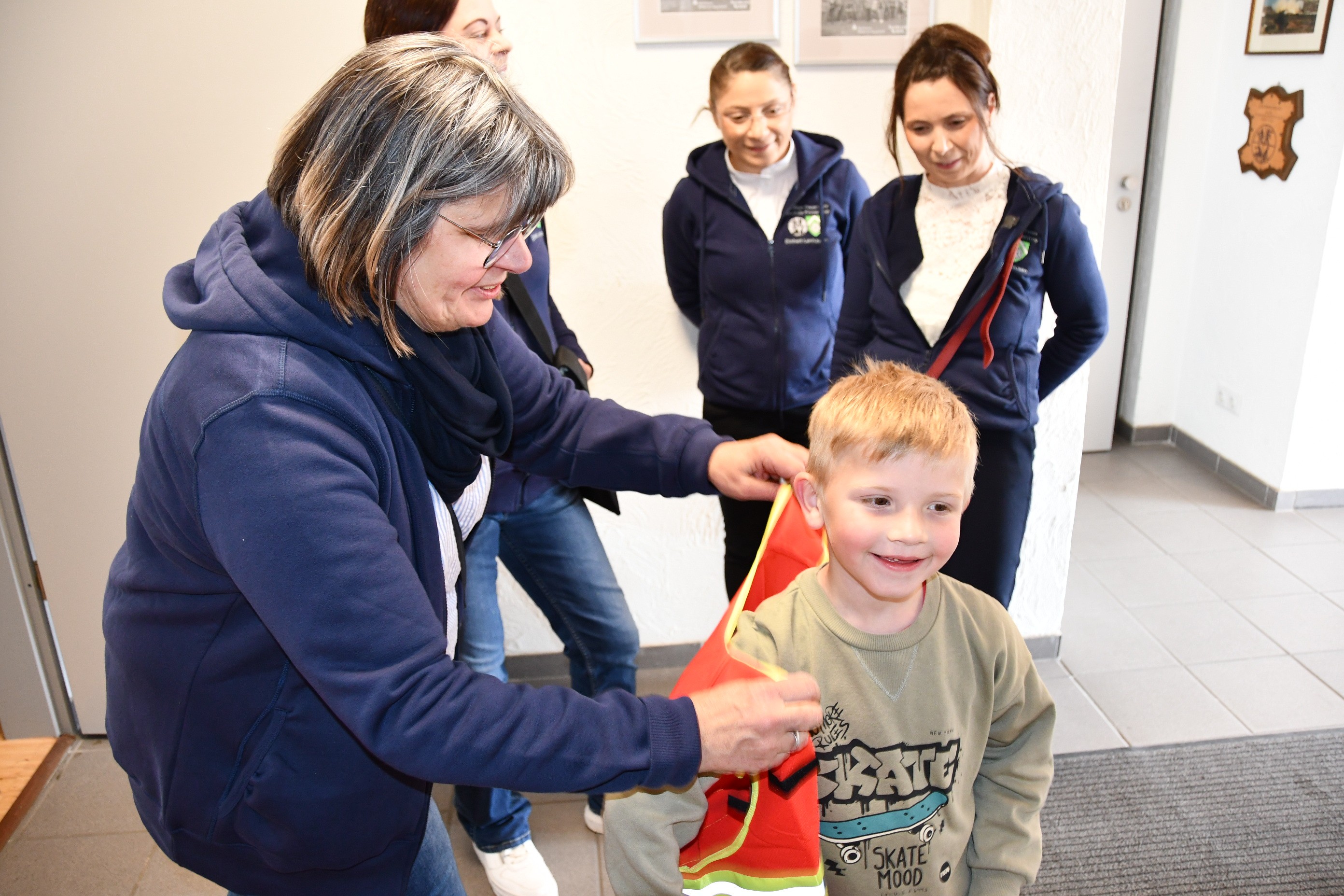 Mikolaj strahlt, als ihm Petra Krempel die Weste der Kinderfeuerwehr anzieht. von Nicole Voss