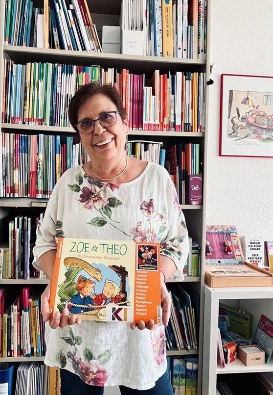 Pilar Calero Westermeier vom Kommunalen Integrationszentrum des Kreises Olpe präsentiert hier das Kinderbuch „Zoe und Theo im Dinosaurier-Museum. von Kreis Olpe