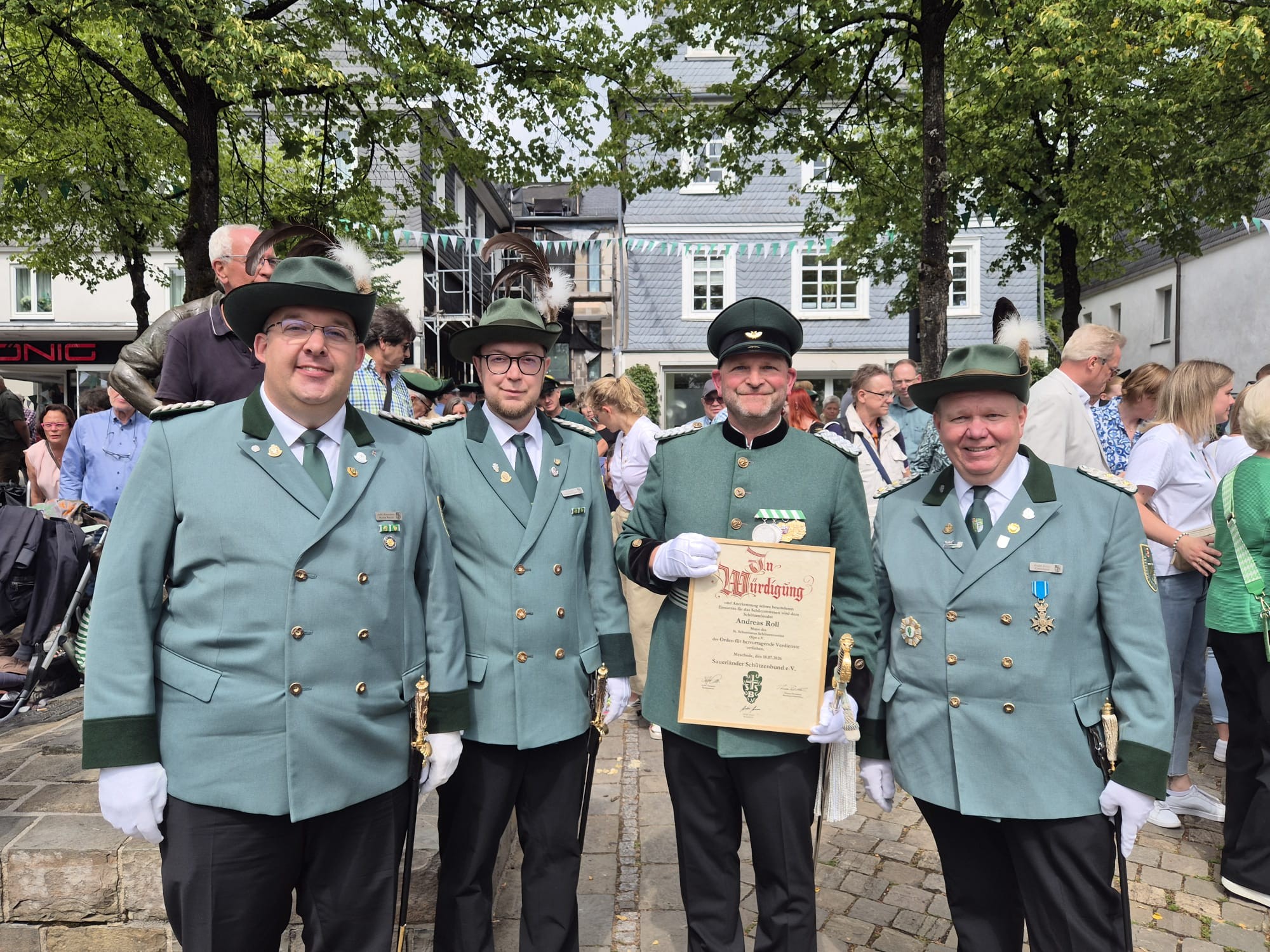 Schützenfestsamstag 2026 auf dem Olper Marktplatz. Kreisoberst André Arenz, Patrick Henze und Martin Wenzel (v.r.) ehren Major Andreas Roll. von privat