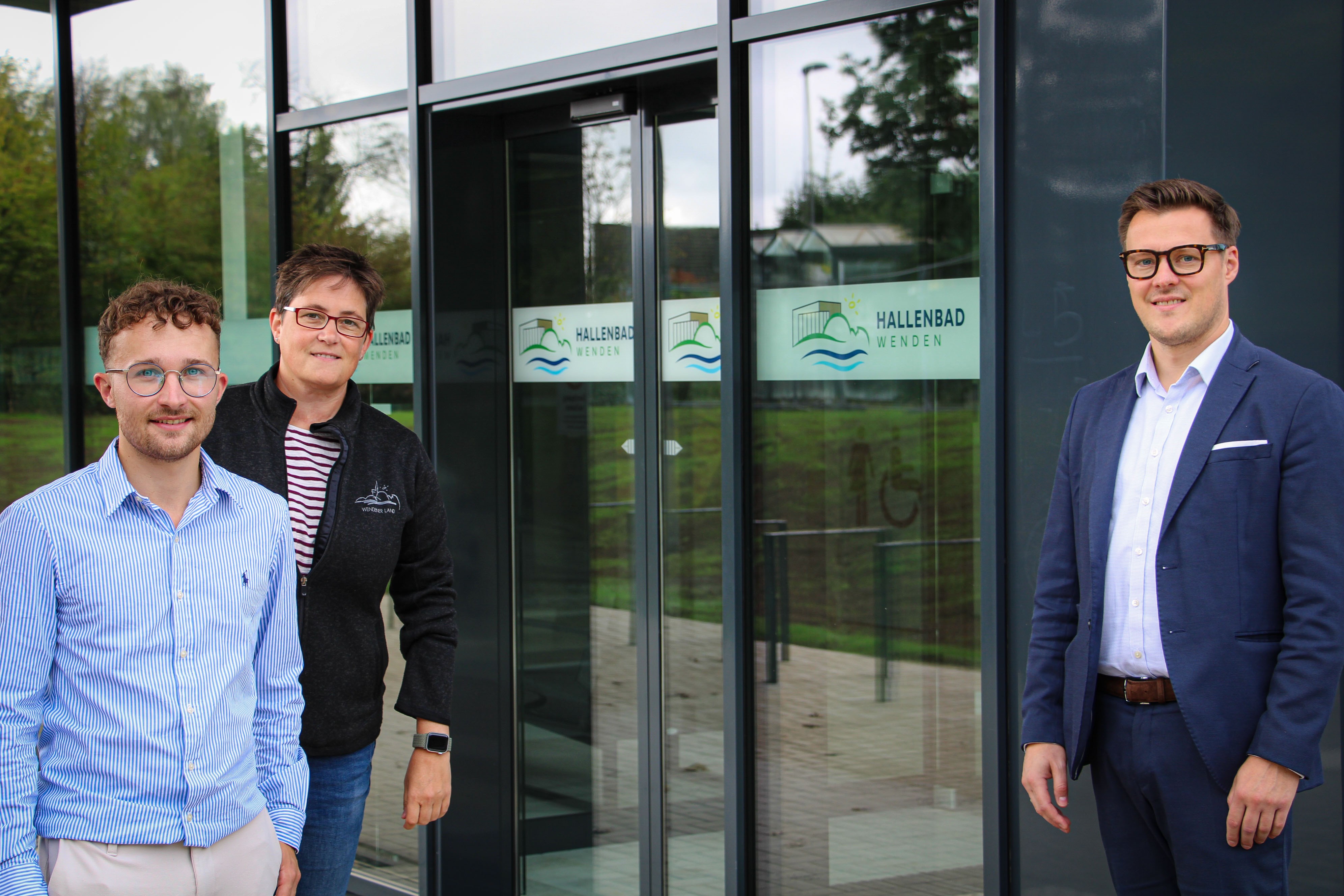 Schwimmmeister Nils Latusek, Nina Stahl und Thomas Munschek (v.l.) von der Gemeinde Wenden vor dem Eingang des neuen Hallenbades. von Lorena Klein